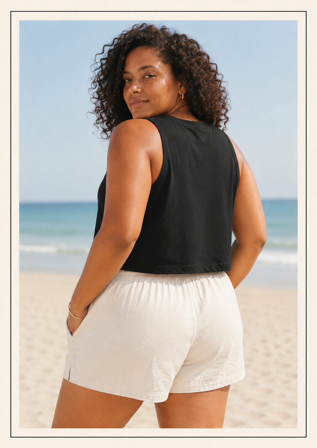 Woman wearing a black sleeveless top and white shorts on a beach.